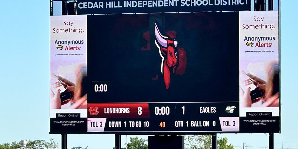 40ft by 20ft LED videoboard at Cedar Hill ISD Longhorn Stadium, showing the game score and down and distance with full-height sponsor panels either side