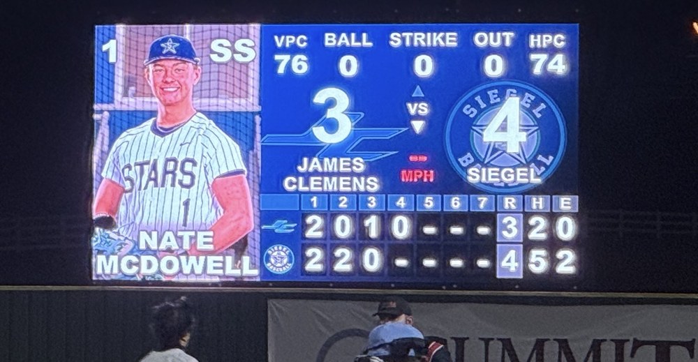 27ft by 14ft LED videoboard at Siegel High School baseball at night, showing a batter card, pitch counts, balls and strikes and a full inning-by-inning line score
